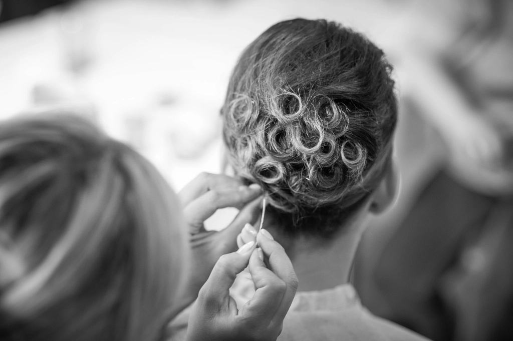 Zwart-witfoto: een hairstylist steekt een opgestoken bruidskapsel vast met een speld